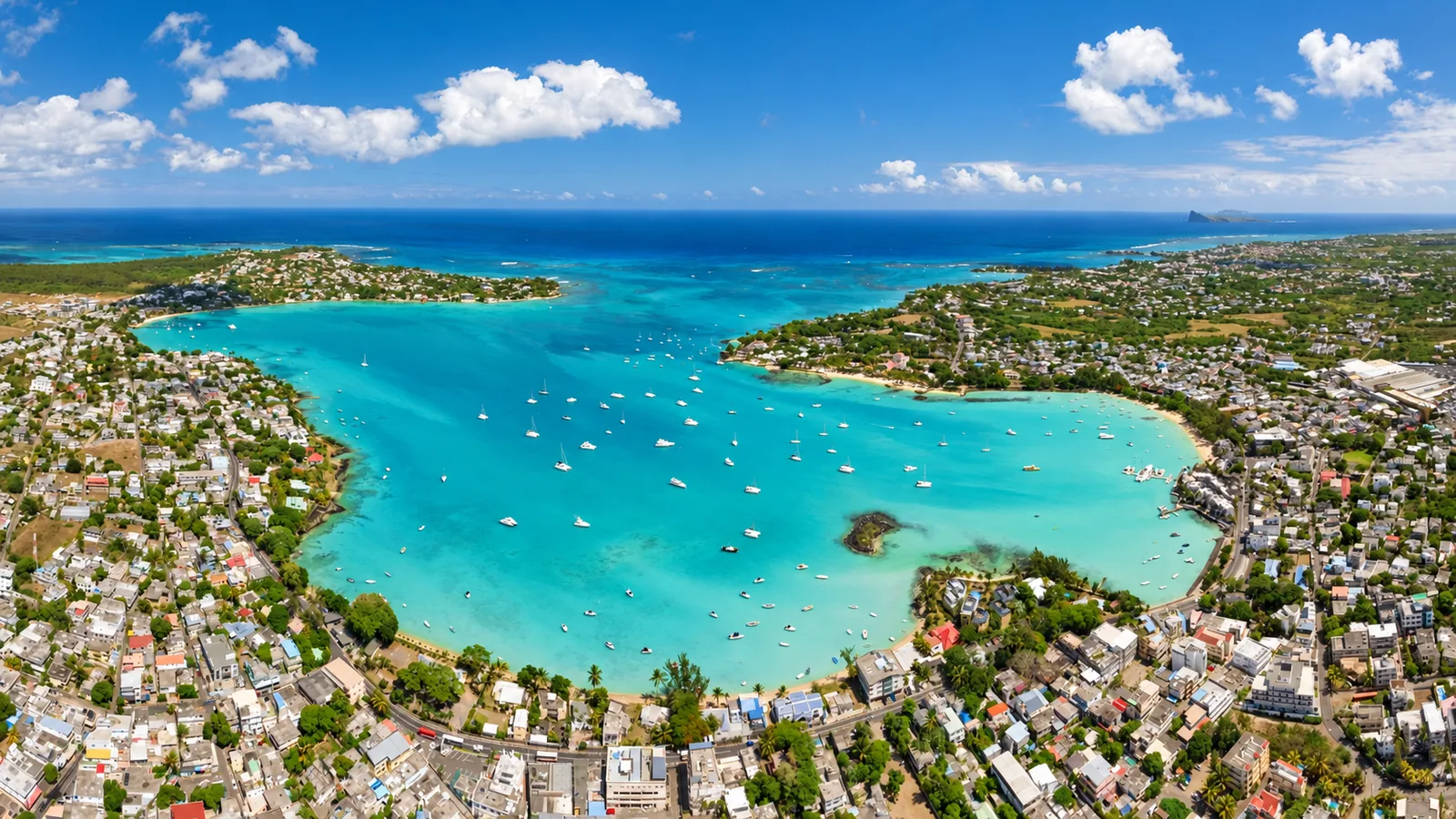 Aerial view of Grand Baie with turquoise lagoon, anchored boats and coastal buildings