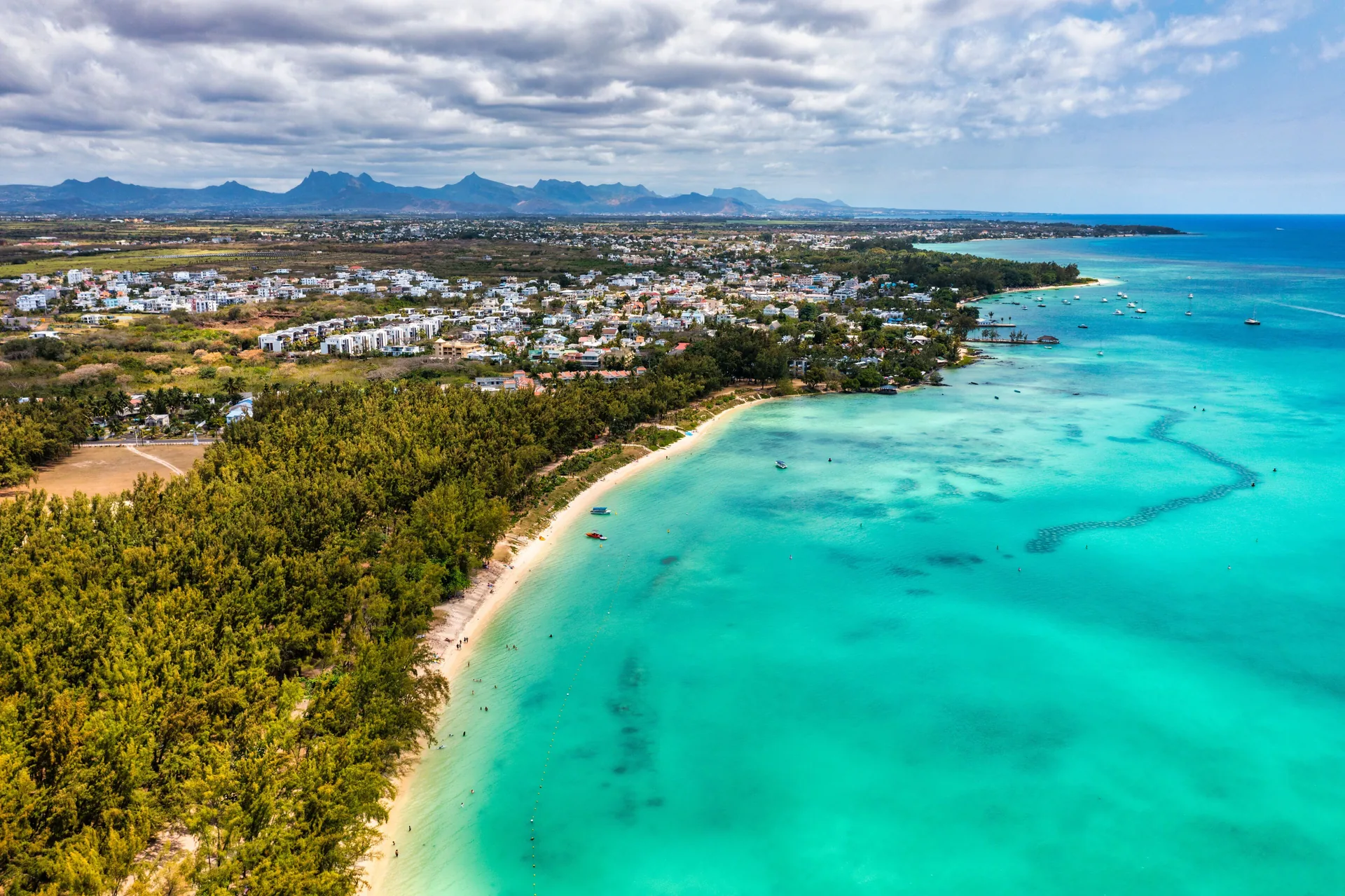 Aerial view of a sandy beach, coastal trees and a turquoise lagoon in Mauritius