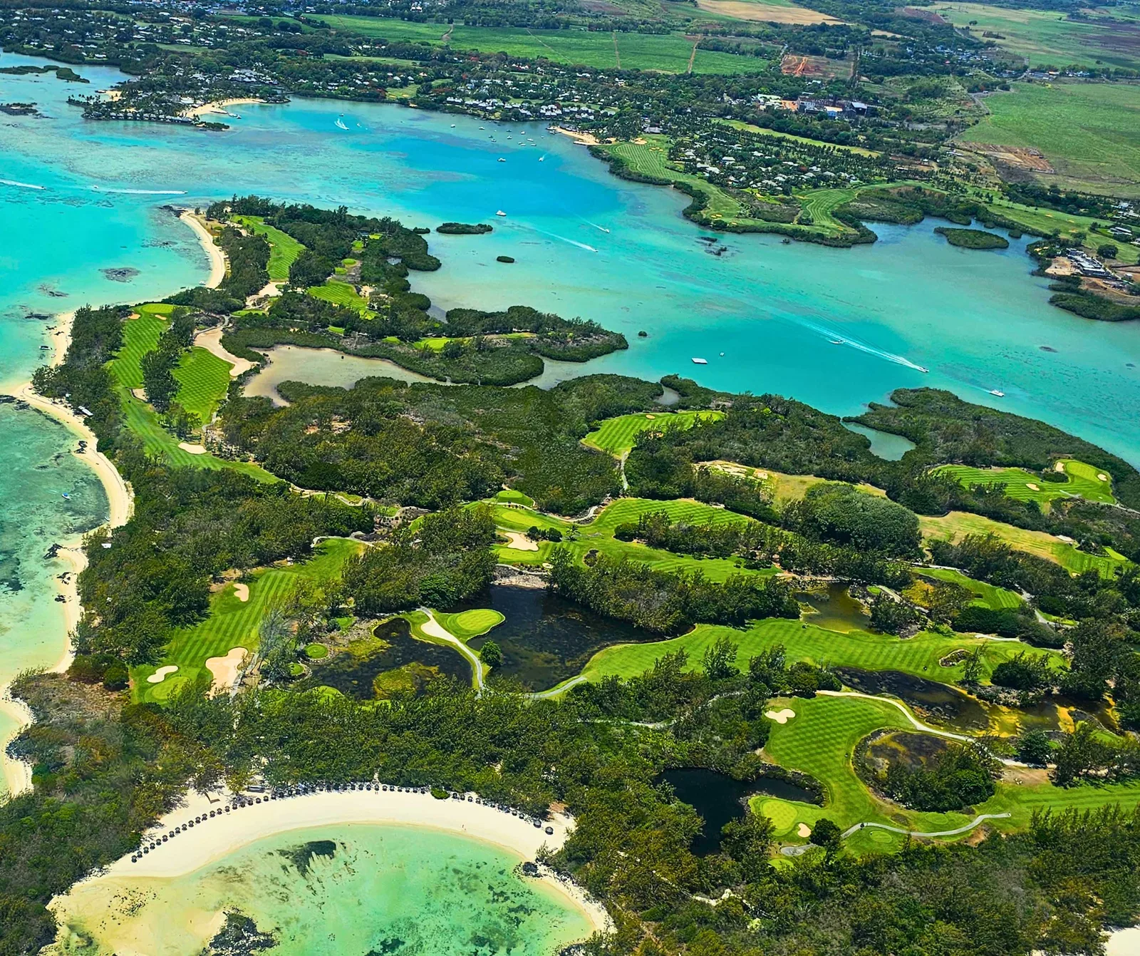 Aerial view over Île aux Cerfs in Mauritius, showing turquoise lagoon channels, sandy beaches, green vegetation and the island’s golf course.