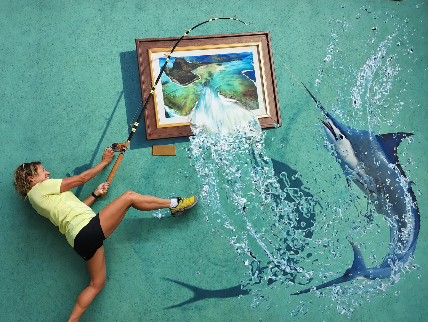 Visitor posing with a fishing-themed optical illusion at Curious Corner of Chamarel in Mauritius.
